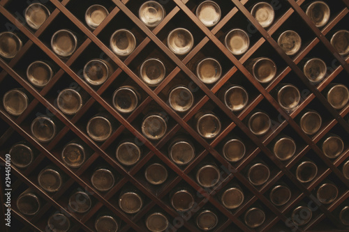 Old bottles of wine on the wall of dark wine cellar. Close-up. Background, pattern, texture. Abstract, design.