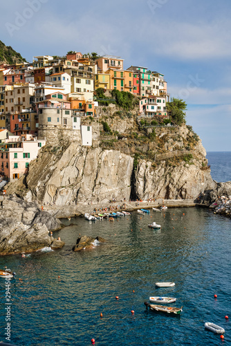 Obraz na płótnie Manarola, Cinque Terre, Italy - August 17, 2019: Picturesque village in the province of La Spezia. Colorful houses on the coastal cliffs. Ligurian Sea Bay with moored boats w salonie