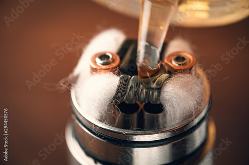 Rebuildable dripping atomizer or RDA for vaping or e-cigarette with coil and cotton stripes wetted with e-liquid photo