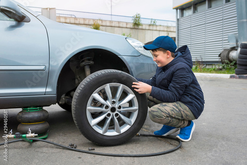  Apprentice auto mechanic changes the wheel of a car.  Auto repair concept. © Andrii