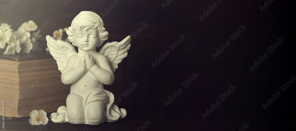 Sympathy card. Guardian angel, spring flowers and old book on dark background with copy space Sympathy card. Guardian angel, spring flowers and old book on dark background with copy space