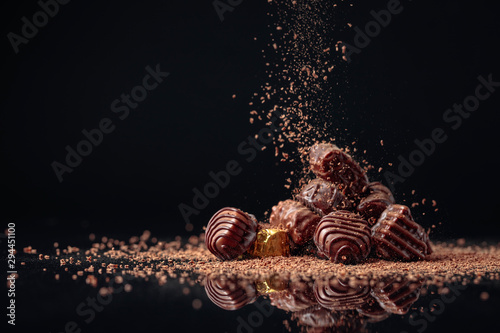 Leinwand Poster Chocolate candies on a black background sprinkled with chocolate chips