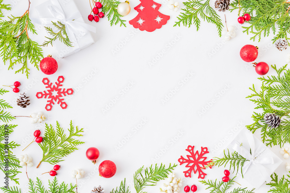 Flat lay frame with evergreen tree branch, christmas decorations and gift box on a white background Flat lay frame with evergreen tree branch, christmas decorations and gift box on a white background