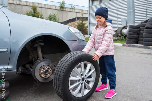  Little girl in a car service, on replacing wheel tires and servicing a vehicle suspension. Auto repair concept.