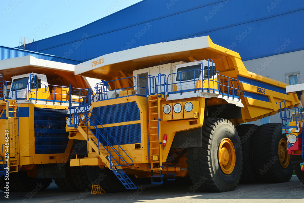 Heavy-duty truck warehouse at autoworks. Giant mining dump trucks manufacture by the heavy vehicle plant. Coal mining, granite, gravel, sand. Heavy-duty truck warehouse at autoworks. Giant mining dump trucks manufacture by the heavy vehicle plant. Coal mining, granite, gravel, sand.