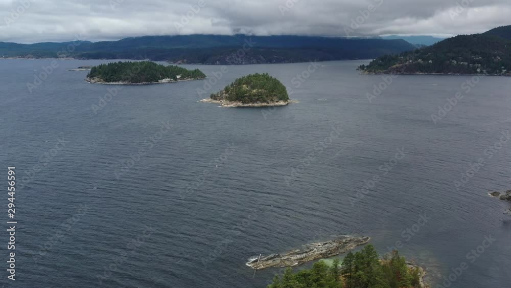 Aerial view over inlet, ocean and island with boat and mountains in beautiful British Columbia. Canada. 4K.
