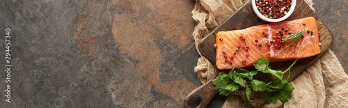 top view of raw fresh salmon with peppercorns, parsley on wooden cutting board on rustic cloth, panoramic shot