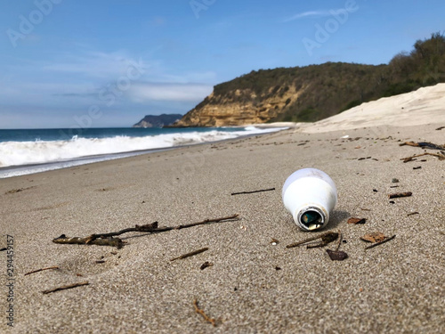 Playa contaminada, con restos tecnologicos y de uso cotidiano, un foco en la arena photo