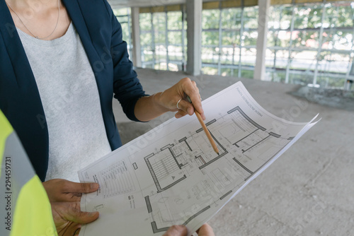 Male architect and female, manager talking about architectural plan at construction site photo