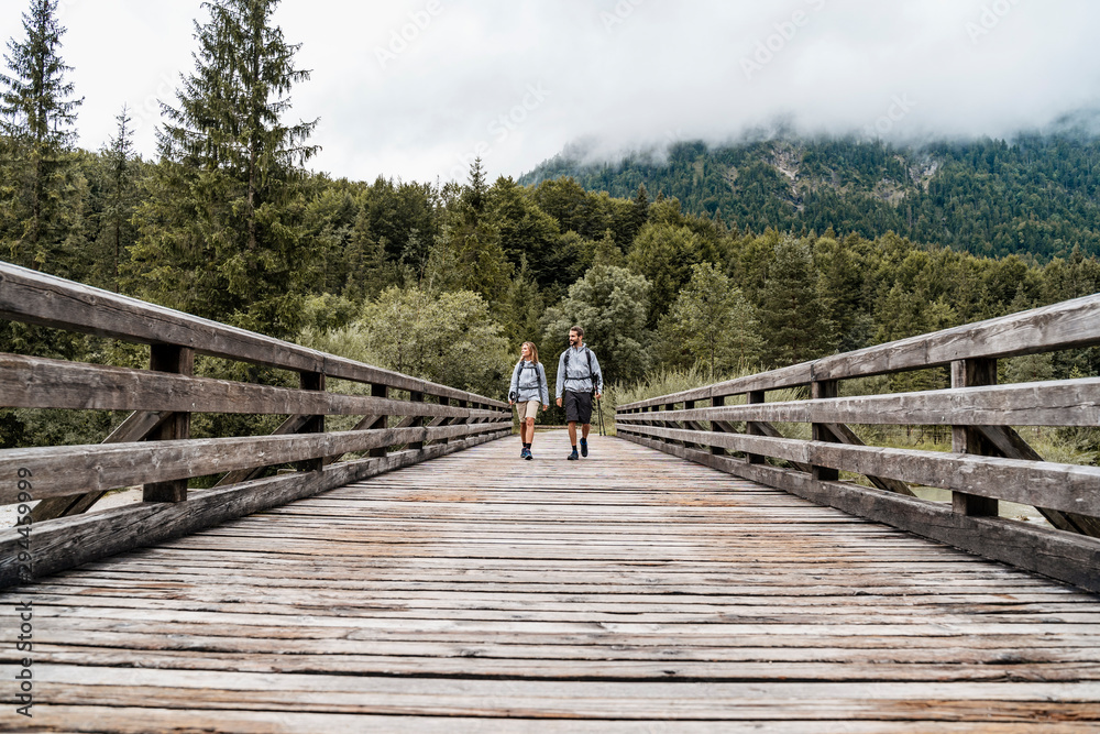 Young couple on a hiking trip walking on wooden, bridge, Vorderriss, Bavaria, Germany Young couple on a hiking trip walking on wooden, bridge, Vorderriss, Bavaria, Germany