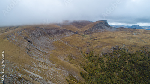 Wild mountainous place in autumn with yellow, red and green trees.