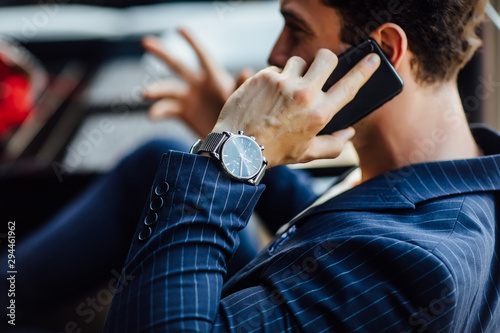 Portrait of bearded successful man sitting in cafe near windows, speak with someone by phone. Have a expensive watch.