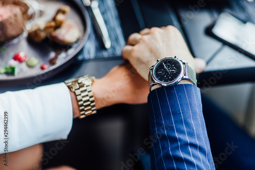 Close up photo, two person holding hands with expensive watch.
