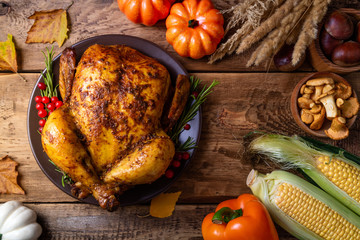 Cooked chicken for Thanksgiving Day. Baked whole chicken or turkey with autumn vegetables, mushrooms and berries for festive dinner on wooden table. Thanksgiving Day, holidays concept. Top view
