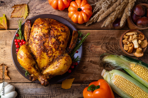 Cooked chicken for Thanksgiving Day. Baked whole chicken or turkey with autumn vegetables, mushrooms and berries for festive dinner on wooden table. Thanksgiving Day, holidays concept. Top view