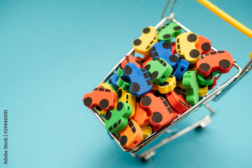 mini toy rubber cars in supermarket trolley on blue background