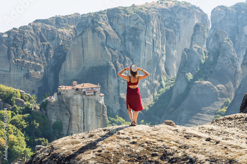  Girl in a red dress stands on a stone in Meteora, Greece