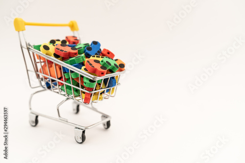 mini toy rubber cars in supermarket trolley on white background © Pavel