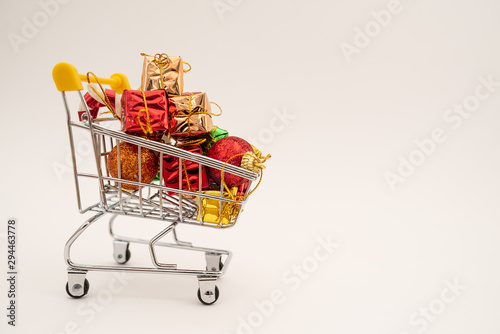 New Year's gifts and toys in supermarket trolley on white background. Christmas shopping concept