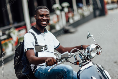 Skip classes. Appealing male student sitting on motorbike in street. Funny African student.