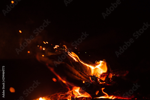 Beautiful abstract background on the theme of fire, light and life. Burning red hot sparks fly from large fire in the night sky. Burning embers glowing flying over black background.