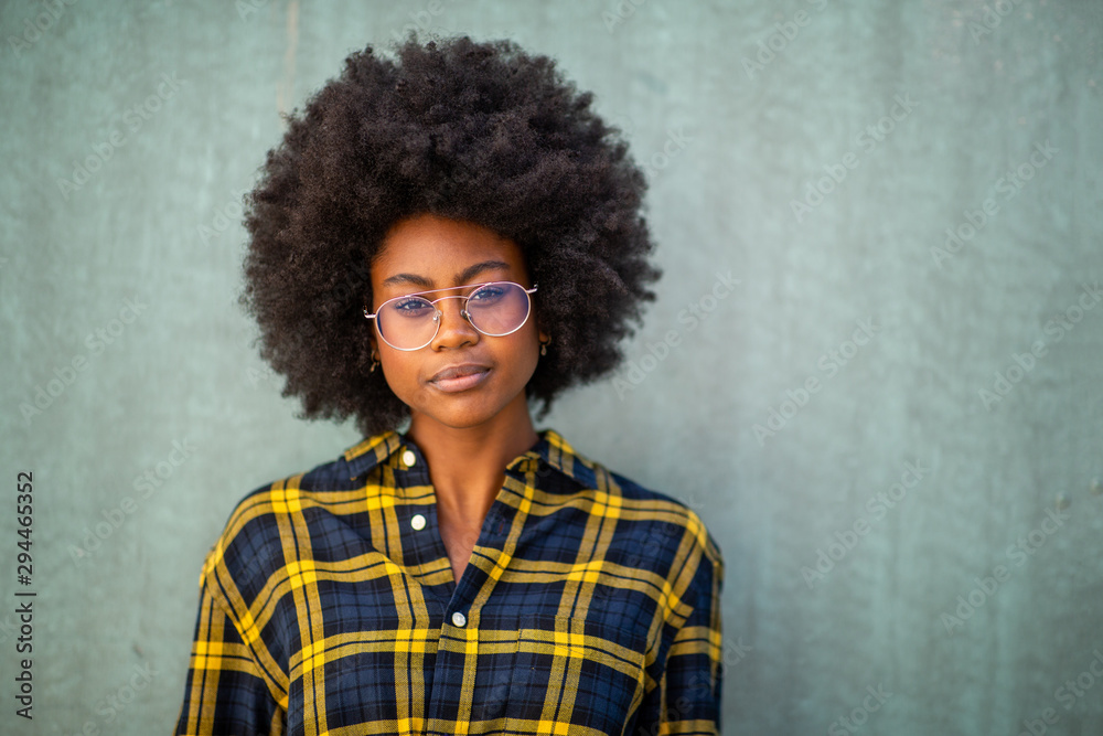 Close up front of beautiful young african american woman with glasses against green wall Close up front of beautiful young african american woman with glasses against green wall