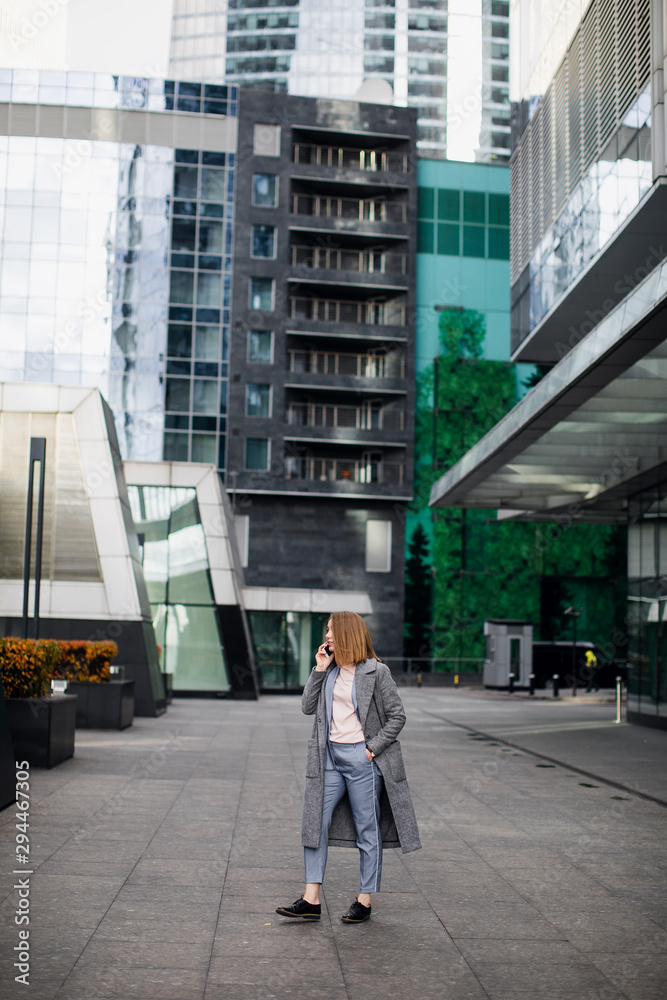Happy business woman talking on phone. Office building background