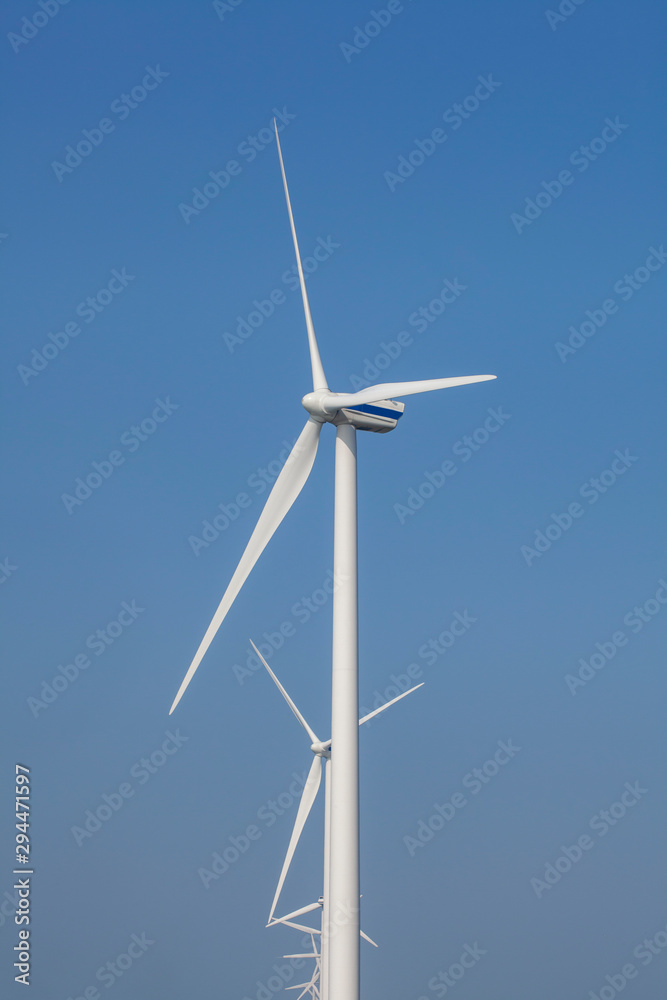 A Modern Wind Farm consisting of Wind Turbines with Two and Three Blades along the Shore of Veluwemeer under Partly Cloudy and Blue Sky in the Netherlands A Modern Wind Farm consisting of Wind Turbines with Two and Three Blades along the Shore of Veluwemeer under Partly Cloudy and Blue Sky in the Netherlands