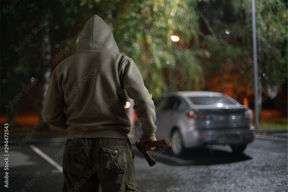 A man with an ax is about to damage the car at night. A man with an ax is about to damage the car at night.