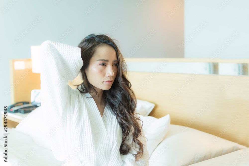 Beautiful asian woman long brown hair wearing white bathrobe on bed just woke up sexy look in the morning time.