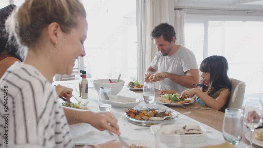 Multi Generation Family Sitting Around Table At Home Eating Meal Together Multi Generation Family Sitting Around Table At Home Eating Meal Together