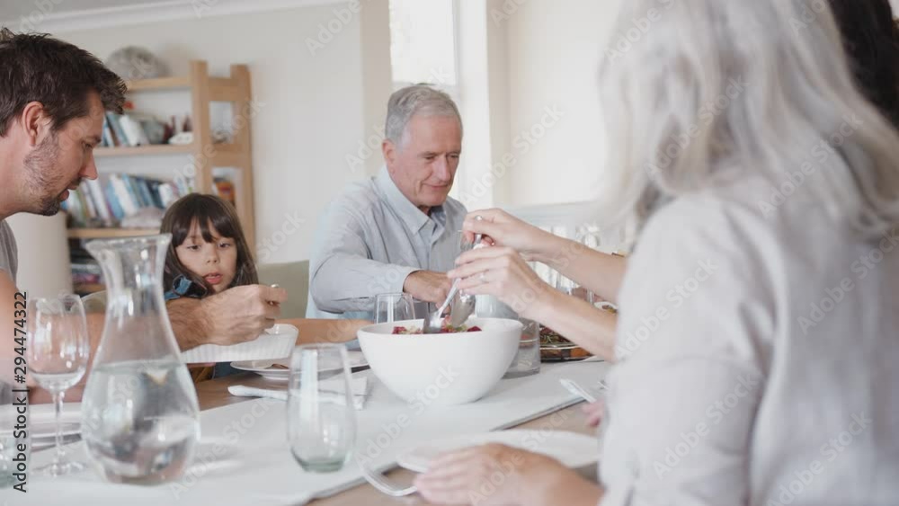 Multi Generation Family Sitting Around Table At Home Eating Meal Together Multi Generation Family Sitting Around Table At Home Eating Meal Together