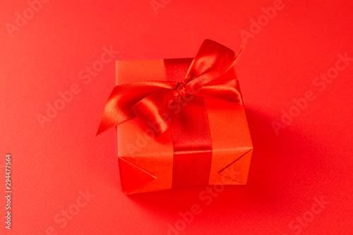 Christmas composition. Red gift box with a red ribbon on a red background. View from above. A Christmas gift