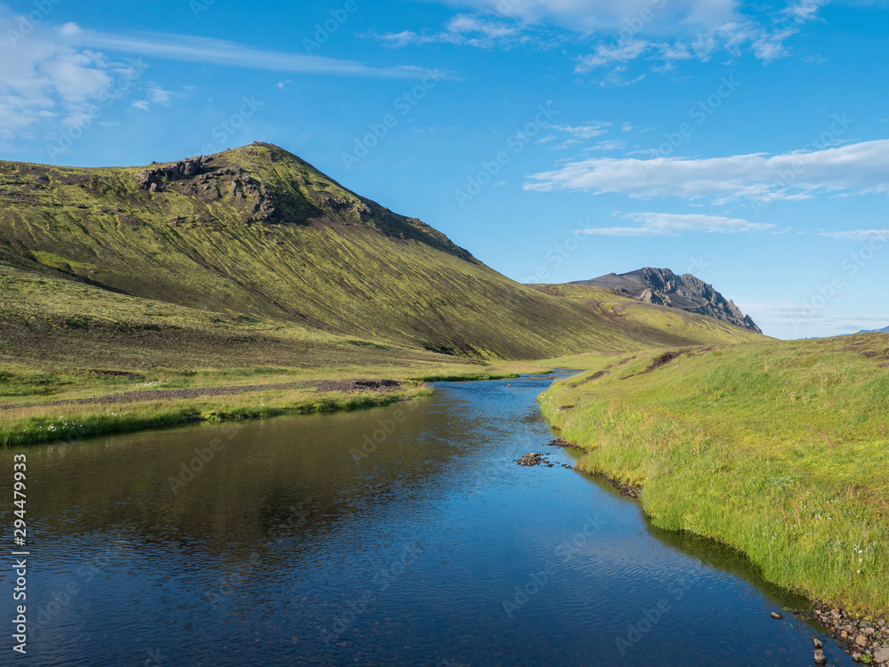 Beautiful green hills, lush grass and blue river next to camping site on Alftavatn lake. Summer sunny day, landscape of the Fjallabak Nature Reserve in Highlands Iceland part of Laugavegur hiking