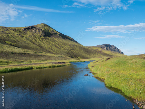 Beautiful green hills, lush grass and blue river next to camping site on Alftavatn lake. Summer sunny day, landscape of the Fjallabak Nature Reserve in Highlands Iceland part of Laugavegur hiking