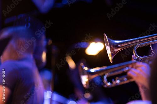 Trumpet players of a big band section playing their horns in blue stage lighting