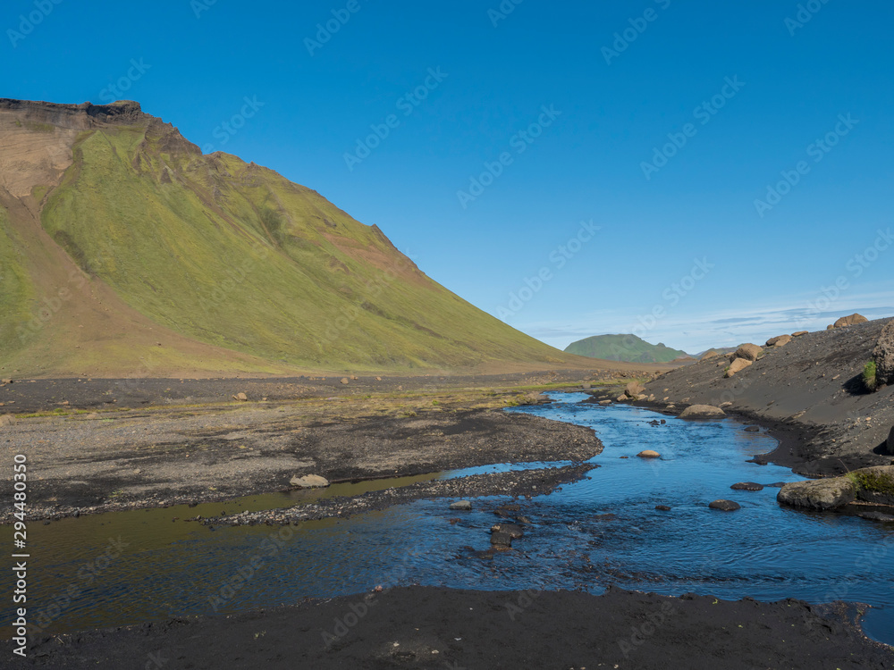 Blue river stream and green Hattafell mountain in Volcanic landscape behind Emstrur camping site in area of Fjallabak Nature Reserve in Highlands region of Iceland