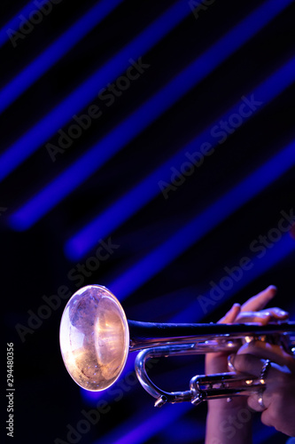 A musician playing a trumpet with a blue line pattern in the background