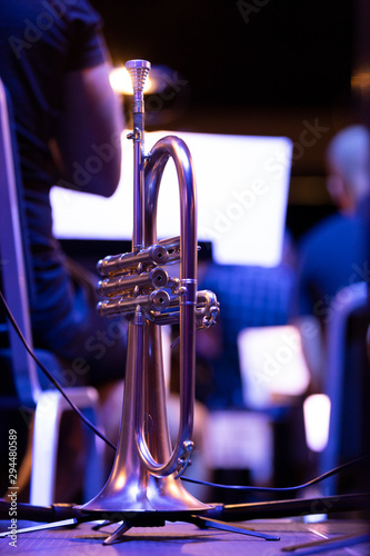 A matte finish flugelhorn on a stand with a music stand light shining bright behind the mouthpiece