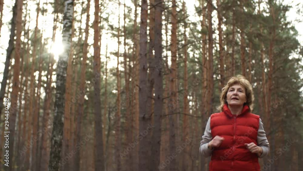 Tilt down of retired Caucasian woman running alone in forest Tilt down of retired Caucasian woman running alone in forest