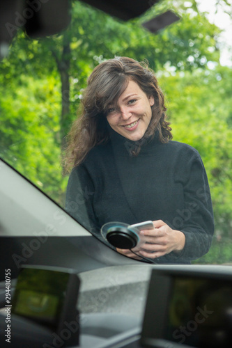 Portrait smiling young woman with smart phone accessing car share