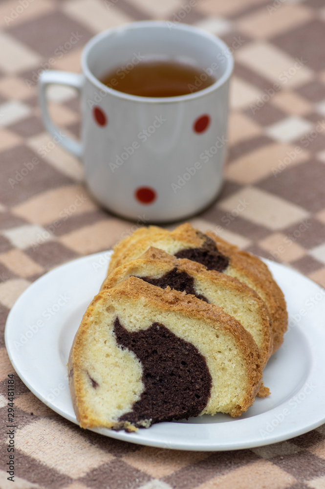 Gugelhupf on white plate on picnic blanket, very tasty edible two-colored Czech sweet cake called babovka, sliced ready to eat