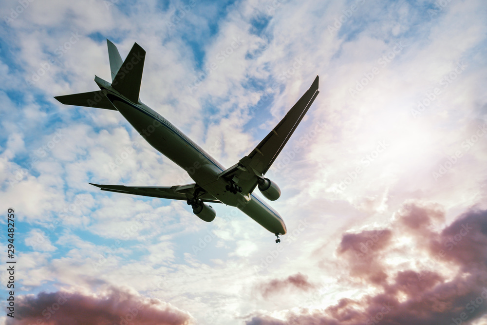 Obraz premium A soaring plane amid cloud sky and sun.