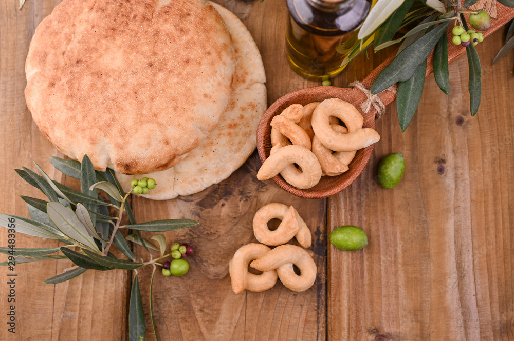 resh and tasty ciabatta on a wooden background. Homemade cakes, olives on fresh branches and oil in a bottle. resh and tasty ciabatta on a wooden background. Homemade cakes, olives on fresh branches and oil in a bottle.