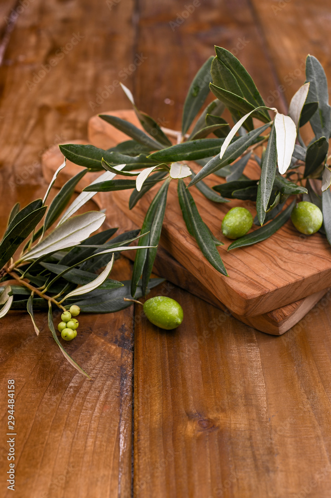 green olives, olives oil and wooden serving board over light wooden background. Top view, free space for text green olives, olives oil and wooden serving board over light wooden background. Top view, free space for text