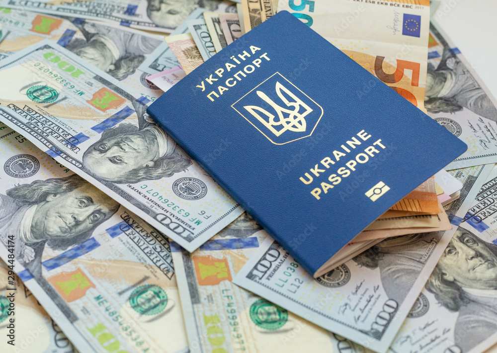 New biometric Ukrainian passport with electronic chip id.Free travel to Europe without visa.Close up shot of travellers document with paper US dollar currency New biometric Ukrainian passport with electronic chip id.Free travel to Europe without visa.Close up shot of travellers document with paper US dollar currency