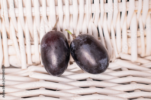 Group of two whole fresh black grape with braided rattan behind