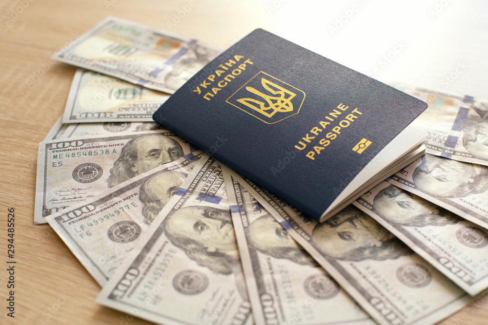 Ukrainian biometric passport and dollars on a wooden background. Money and documents for trip abroad. Documents for immigration. Ukrainian biometric passport and dollars on a wooden background. Money and documents for trip abroad. Documents for immigration.