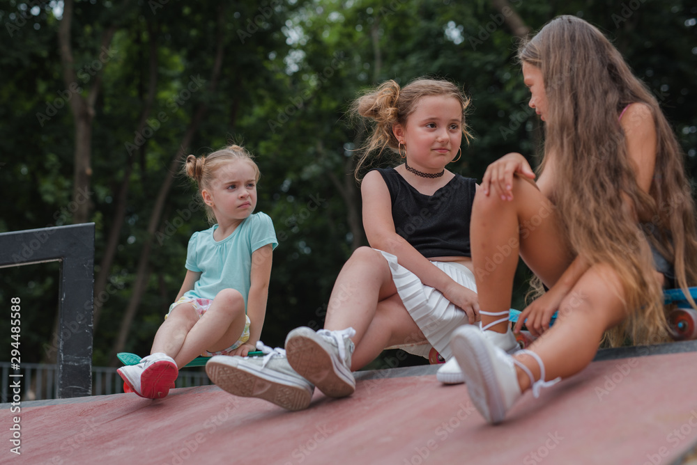 Three young girls skaters best friends hangout at the skate park on sunset .Laughing and fun. Three young girls skaters best friends hangout at the skate park on sunset .Laughing and fun.