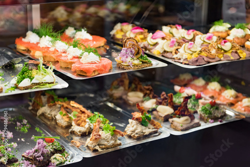 Danish smorrebrod traditional open sandwich at Copenhagen food market store. Many sandwiches on display with seafood and meat, smoked salmon.